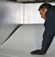 A contractor installing TerraBlock floor insulation in a Clinton crawl space