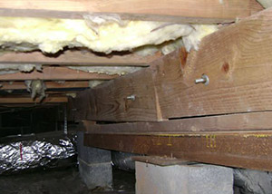 A sagging crawl space with concrete supports and wooden shimming a Sevierville crawl space
